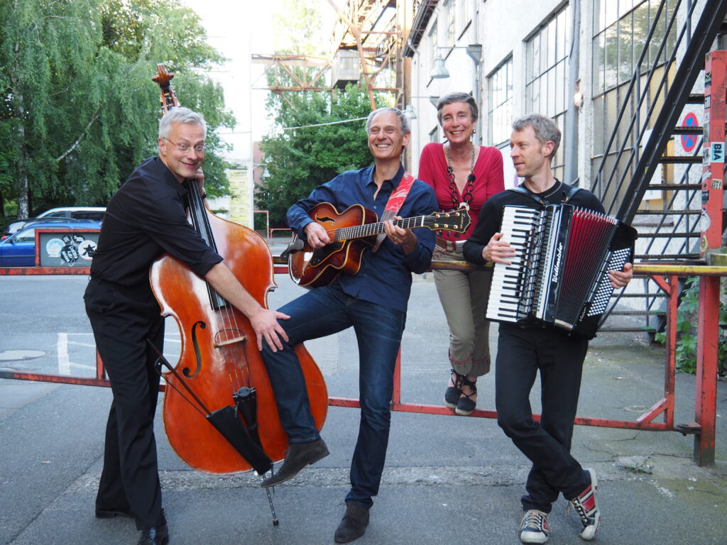 Das Musik Quartett CuadroSol aus Hamburg posiert auf einem alten Insustriegelände mit den Instrumenten Kontrabass, Gitarre und Akkordeon und mit Ihrer Sängerin