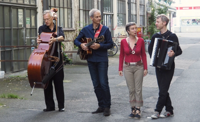 Das Musik Quartett CuadroSol aus Hamburg posiert auf einem alten Insustriegelände mit den Instrumenten Kontrabass, Gitarre und Akkordeon und mit Ihrer Sängerin